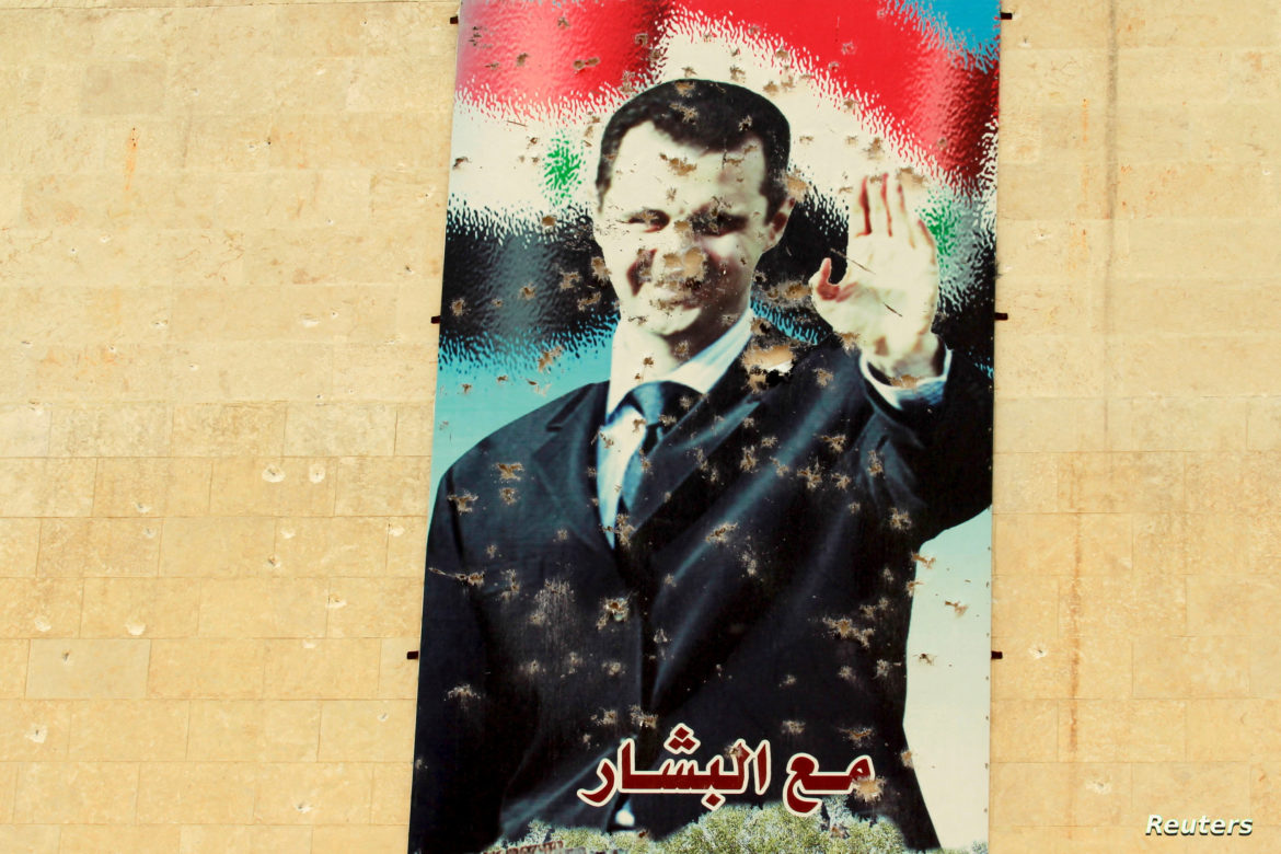 FILE PHOTO: A damaged picture of Syrian president Bashar Al-Assad is seen on a wall in Idlib city, after rebel fighters took control of the area