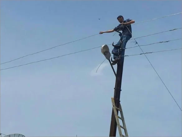 متطوع يوصل أسلاك الكهرباء بإحدى المناطق السورية (الجزيرة)