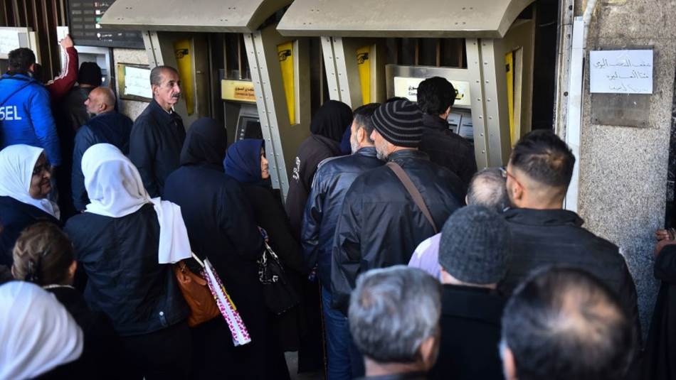 سوريين امام احد الصرفات النقود